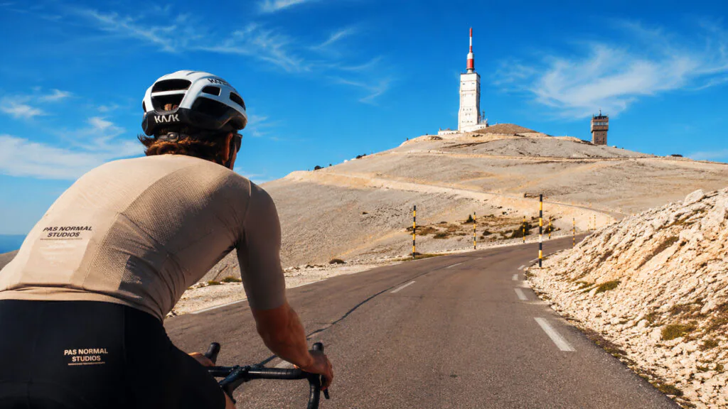 A small group of cyclists ride up Mont Ventoux towards the summit observatory in the distance.